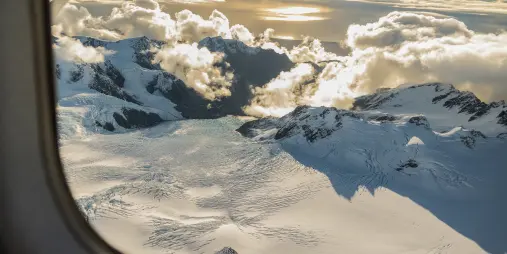 Sunset over Franz Josef Glacier névé captured from aircraft window during scenic flight