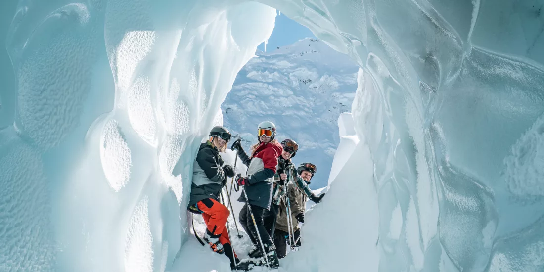 Group of skiers standing inside a sculpted glacier ice cave on the Tasman Glacier.