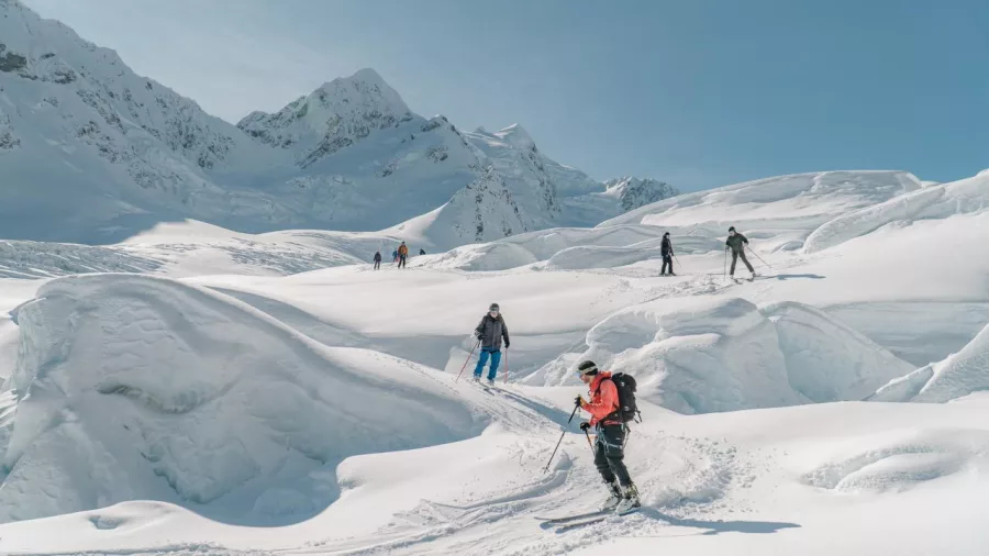 Guided group skiing down gentle glacier slopes surrounded by ice formations.