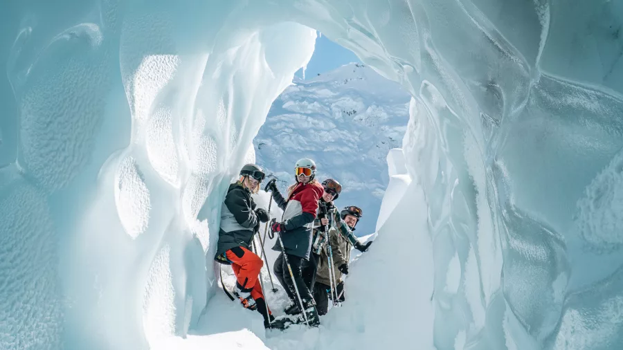 Group of skiers standing inside a sculpted glacier ice cave on the Tasman Glacier.