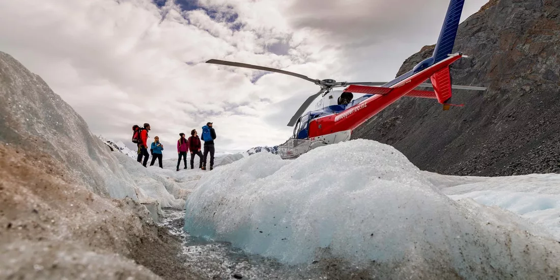 Group of hikers standing beside a helicopter on the Tasman Glacier at the start of their hike.