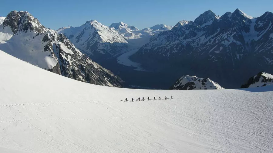 Group of trekkers walking across snowfields on Ball Glacier, overlooking Tasman Valley.