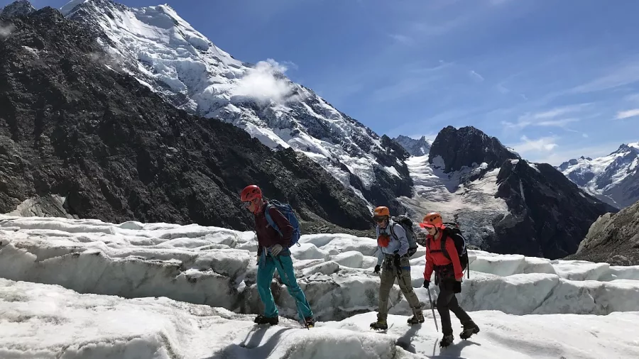 Guided hikers trekking across Ball Glacier with Aoraki Mount Cook rising in the background.