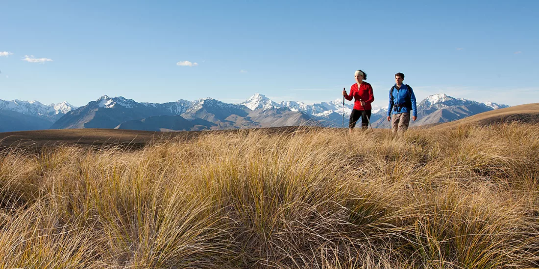 Two hikers walking along Snake Ridge with panoramic views of Aoraki Mount Cook and the Southern Alps.