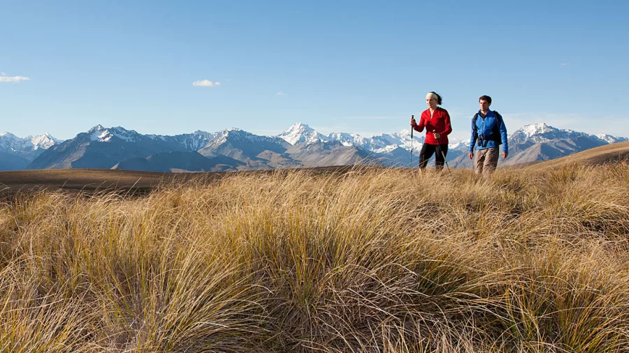 Two hikers walking along Snake Ridge with panoramic views of Aoraki Mount Cook and the Southern Alps.