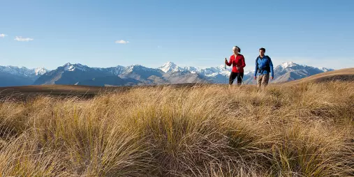 Two hikers walking along Snake Ridge with panoramic views of Aoraki Mount Cook and the Southern Alps.