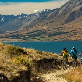 Cyclists riding the Alps 2 Ocean Cycle Trail near Sailor’s Cutting with Lake Benmore and mountain views