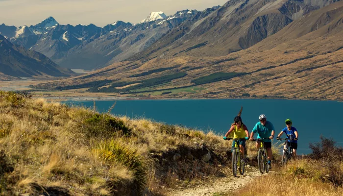 Cyclists riding the Alps 2 Ocean Cycle Trail near Sailor’s Cutting with Lake Benmore and mountain views