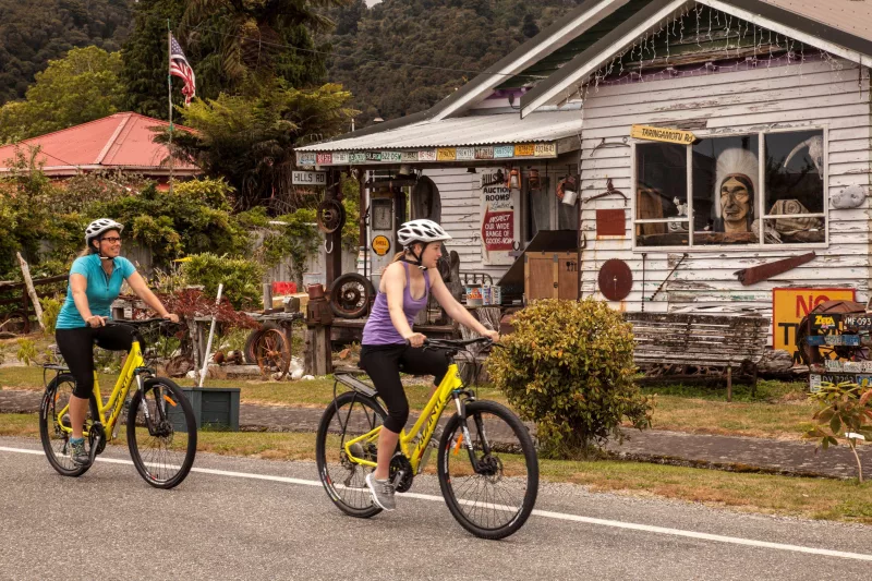 Cyclists riding past a historic building in Ross on the West Coast Wilderness Trail
