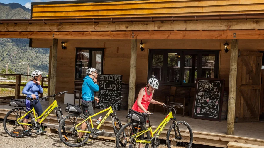 Cyclists stopped outside a rustic café offering meals on the West Coast Wilderness Trail