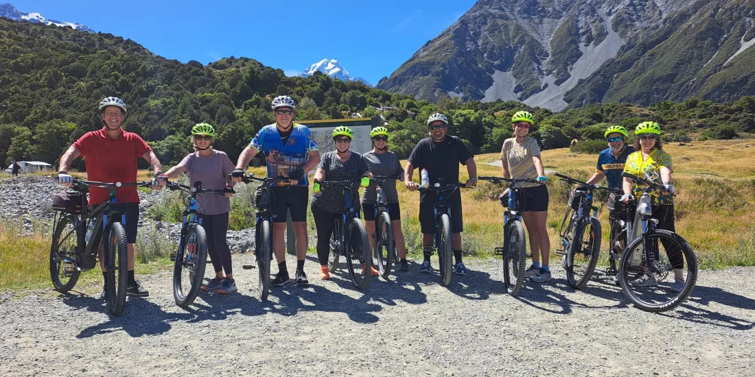 Group of cyclists posing with e-bikes at the start of the Alps 2 Ocean Cycle Trail in Aoraki Mount Cook National Park