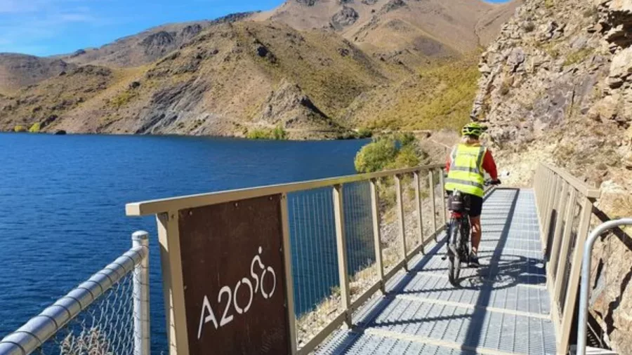 Cyclist crossing bridge on the Alps 2 Ocean Trail alongside Lake Aviemore