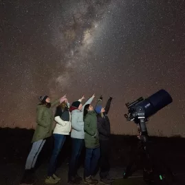 Group of people stargazing under the Milky Way at Lake Tekapo with a telescope in New Zealand's Dark Sky Reserve
