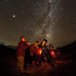 Group of people using telescopes under the Milky Way during a guided stargazing tour at Lake Tekapo