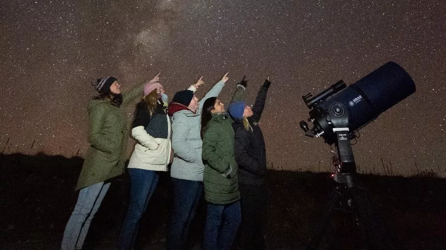 Group of people stargazing under the Milky Way at Lake Tekapo with a telescope in New Zealand's Dark Sky Reserve