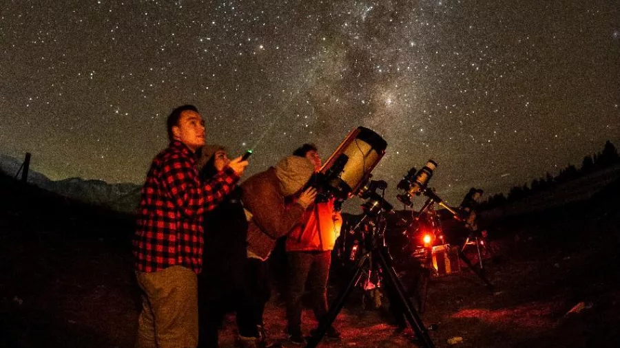 Group of people using telescopes under the Milky Way during a guided stargazing tour at Lake Tekapo