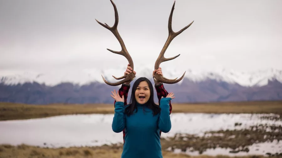 Smiling woman posing playfully with deer antlers during a guided high country tour near Tekapo