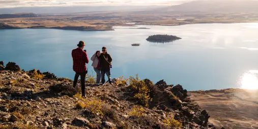 Two people posing for a photo with stunning views over Lake Tekapo from a rocky viewpoint