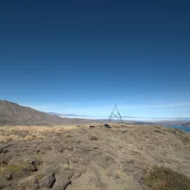 Summit of Mount Hay with trig marker and a view stretching out across the lake and hills beyond