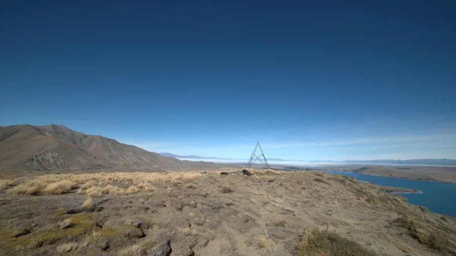 Summit of Mount Hay with trig marker and a view stretching out across the lake and hills beyond