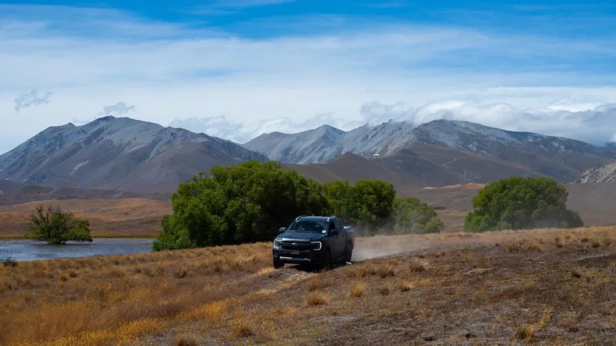 4WD vehicle kicking up dust as it drives along a farm track with Mount Edward in the background