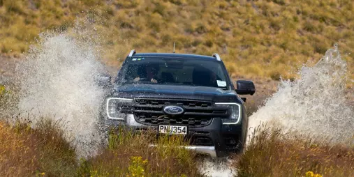Black 4WD vehicle splashing through a muddy stream on the Mount Hay Station 4x4 tour