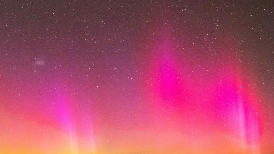 Bright pink and yellow Aurora Australis lights dancing in the sky at Lake Tekapo