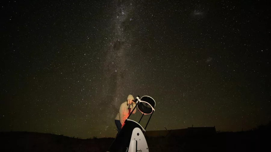 Guest looking through a large telescope beneath the Milky Way during a stargazing tour at Lake Tekapo