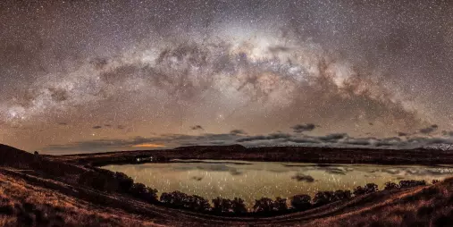 Full arc of the Milky Way reflected in a lake under clear skies at Lake Tekapo