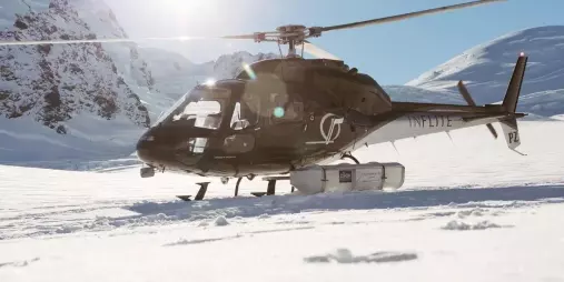Helicopter landed on the Tasman Glacier with snow-covered peaks in the background at Mount Cook