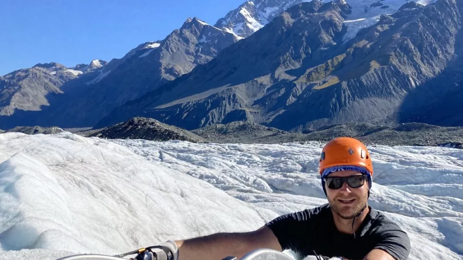 Ice climber pausing on Tasman Glacier with Aoraki/Mount Cook in the background.