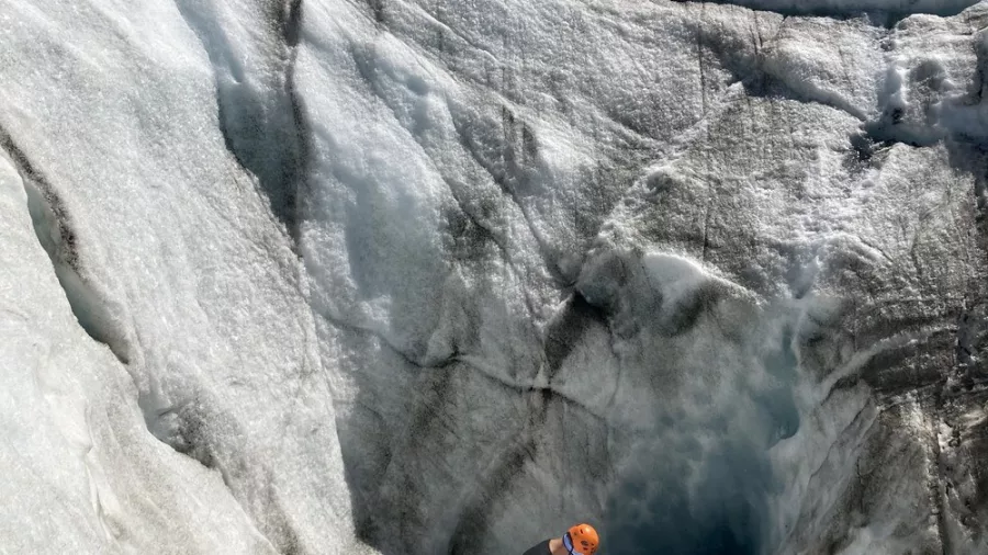 Climber descending into a glacier crevasse on Tasman Glacier, roped in for safety.