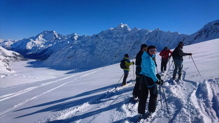 Group of skiers on Tasman Glacier with panoramic views of the Southern Alps near Mount Cook