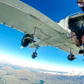 Tandem skydivers leaving the plane high above the Southern Alps