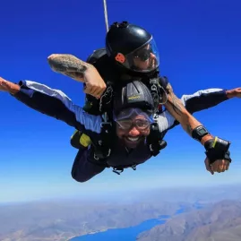 Tandem skydiver flying over lake and mountains near Mount Cook