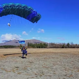 Tandem skydive pair landing with blue parachute at Mount Cook airfield