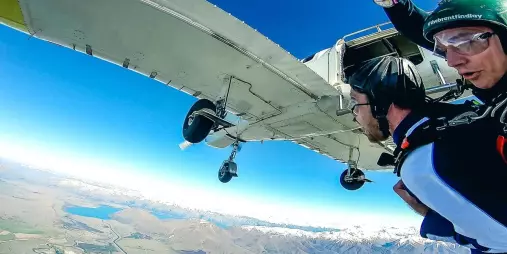 Tandem skydivers leaving the plane high above the Southern Alps