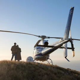 Couple enjoying a romantic moment beside a helicopter at an alpine picnic location near Lake Tekapo