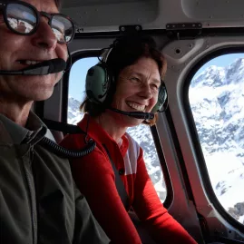 Smiling couple enjoying a scenic helicopter flight over the snow-covered Southern Alps near Lake Tekapo
