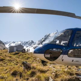 Helicopter parked on an alpine saddle near a hut in the mountains of New Zealand’s South Island