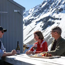 Mackenzie Helicopters pilot hosting two guests at a picnic table set in the mountains of the Southern Alps