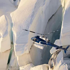 Close-up of a helicopter flying past towering glacial ice formations in New Zealand’s Southern Alps