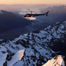 Helicopter flying over the Southern Alps at sunset with Lake Pukaki and the Mackenzie Basin below