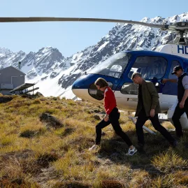 Guests stepping out of a helicopter at a remote alpine hut location near Lake Tekapo