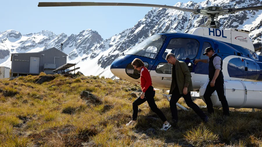 Guests stepping out of a helicopter at a remote alpine hut location near Lake Tekapo