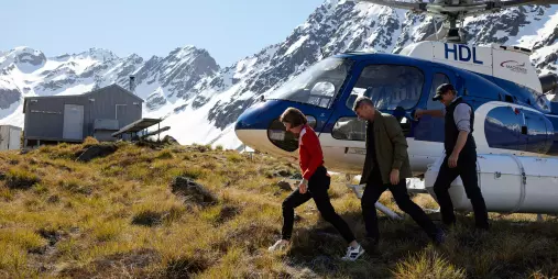 Guests stepping out of a helicopter at a remote alpine hut location near Lake Tekapo