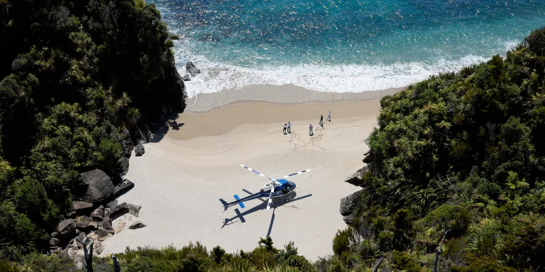 Guests arriving by helicopter on a hidden West Coast beach for a gourmet outdoor picnic