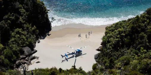 Guests arriving by helicopter on a hidden West Coast beach for a gourmet outdoor picnic