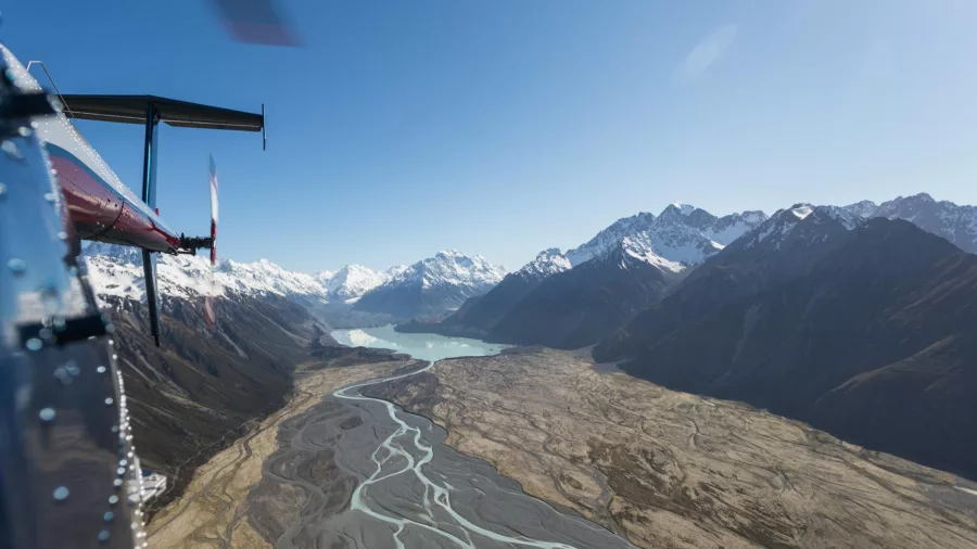 View from a helicopter flying above the braided Godley River towards Lake Tekapo and the Southern Alps