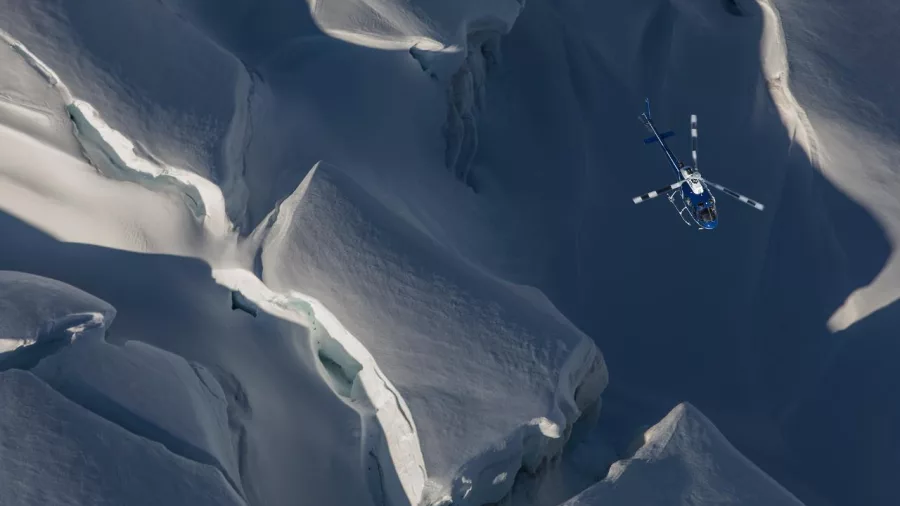 Helicopter flying above deep crevasses in the upper Tasman Glacier, Southern Alps